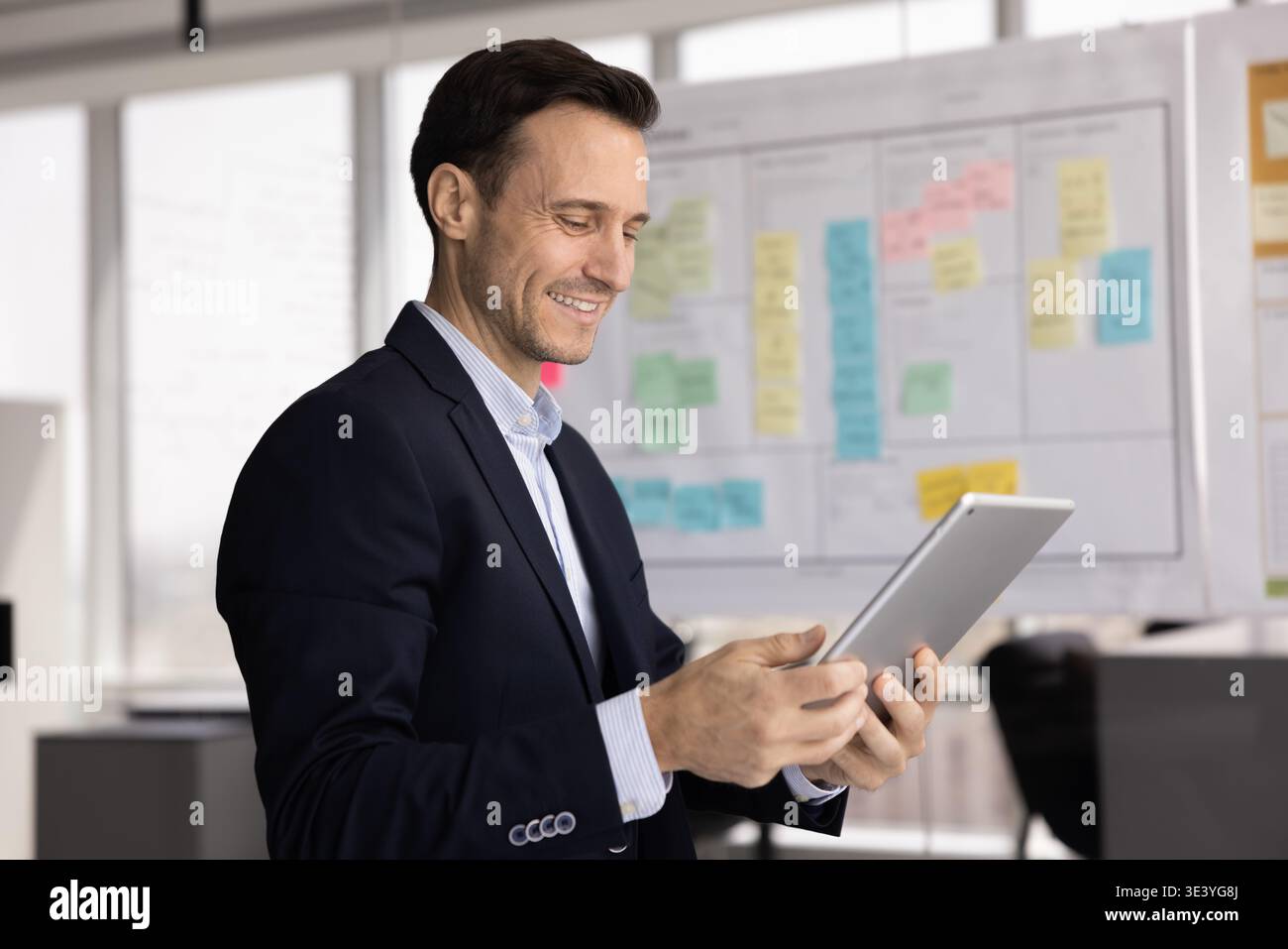 Smiling mid aged businessman using electronic pad in work office Stock Photo