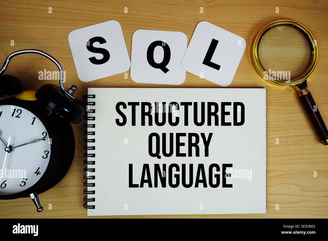 SQL Structured Query Language text written on notepad with magnifying glass and alarm clock on wooden background Stock Photo