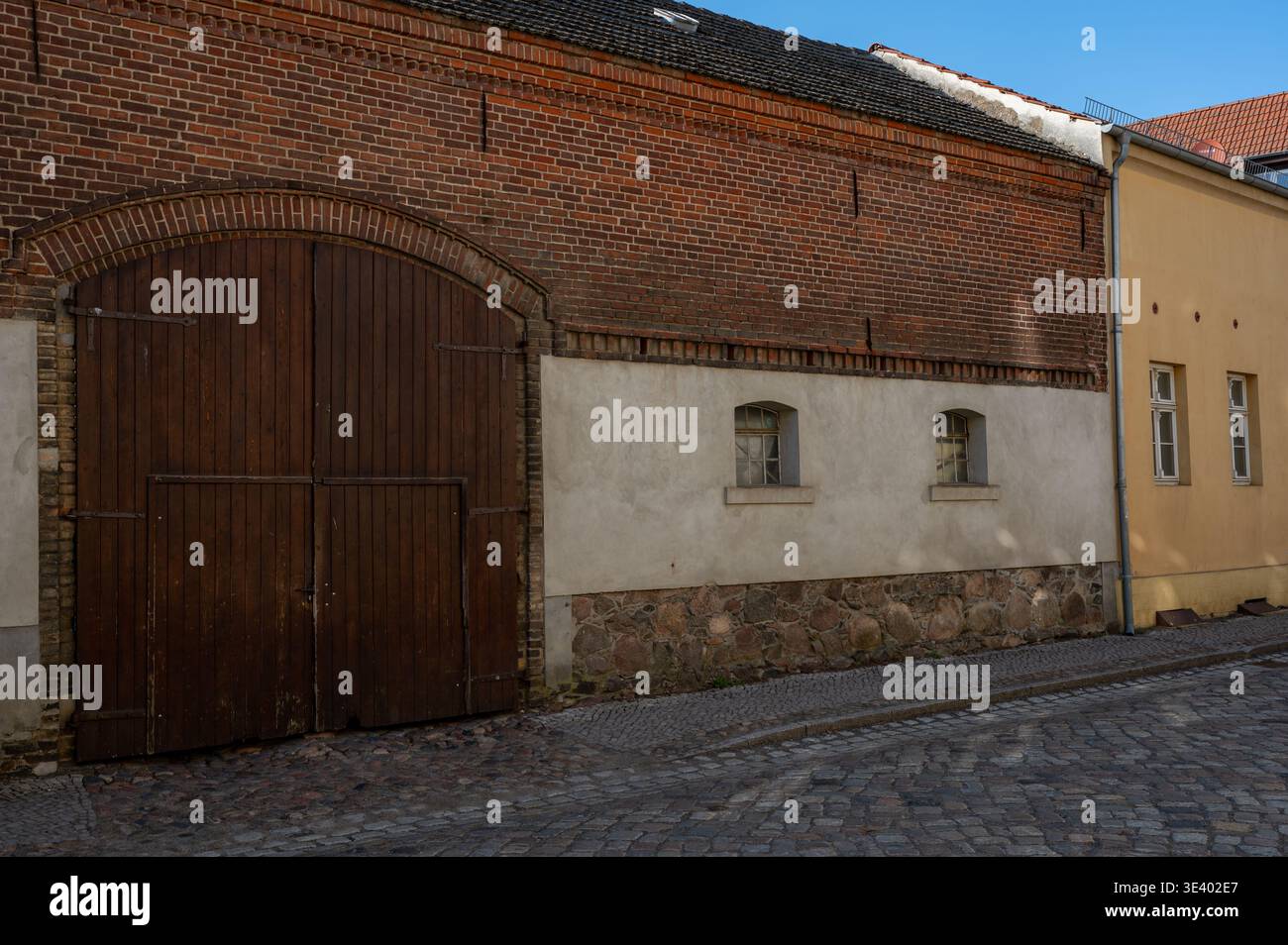 Historic stone and brick building with wooden arched gate Stock Photo