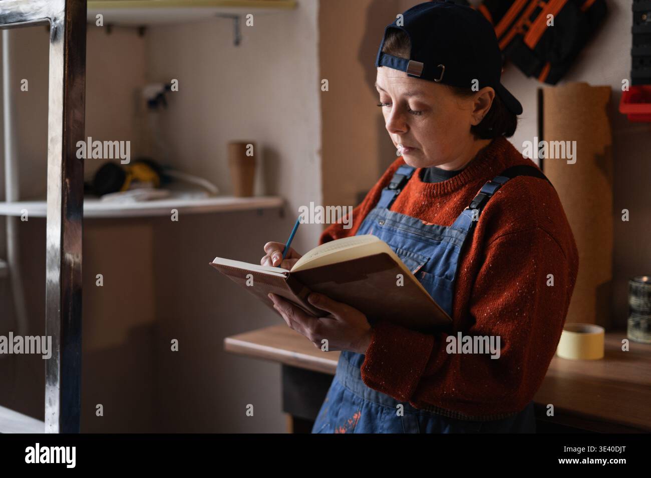 Female repairman writing notes while working in workshop. DIY concept. Stock Photo