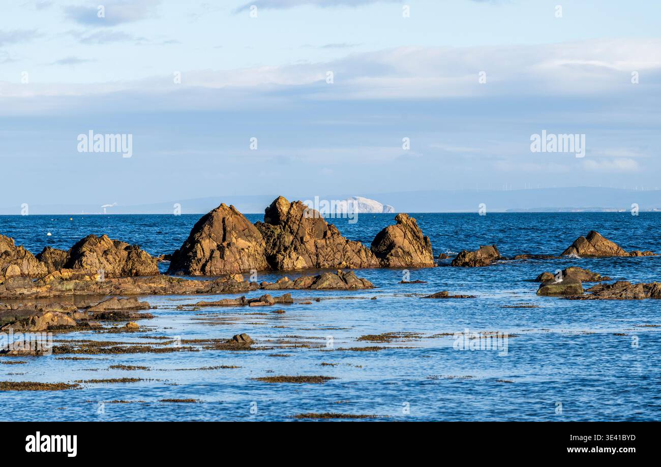 Dramatic coastal view showing Bass Rock on the horizon and rugged rocks ...
