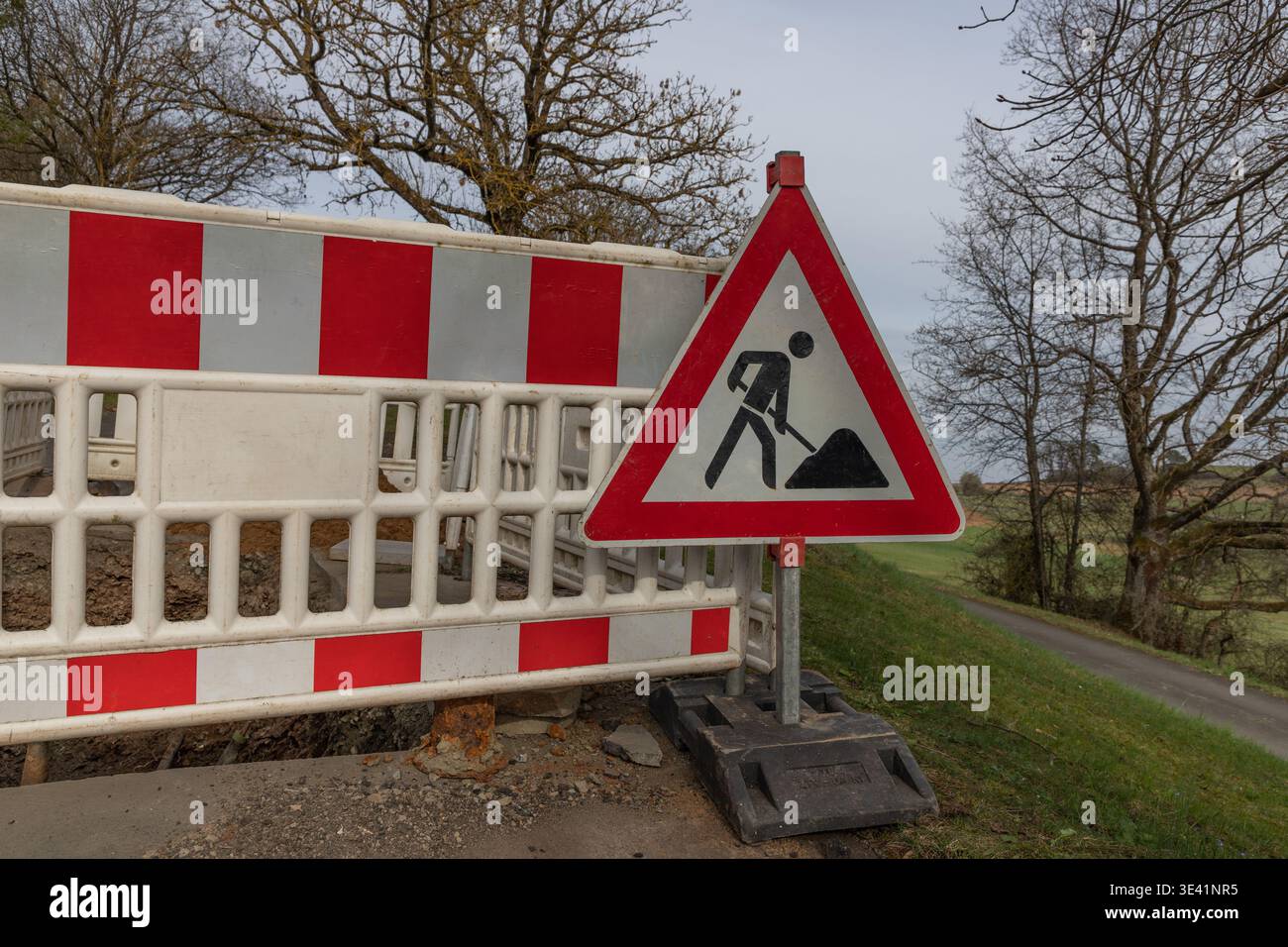 Road works warning sign and safety barrier at construction site on ...