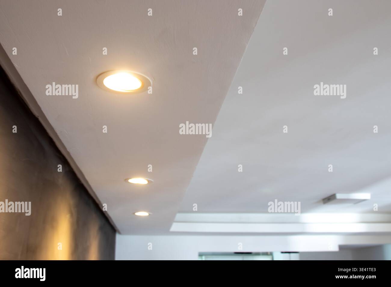 Detail of recessed ceiling lighting with LED spotlights lit in a residential interior. Stock Photo