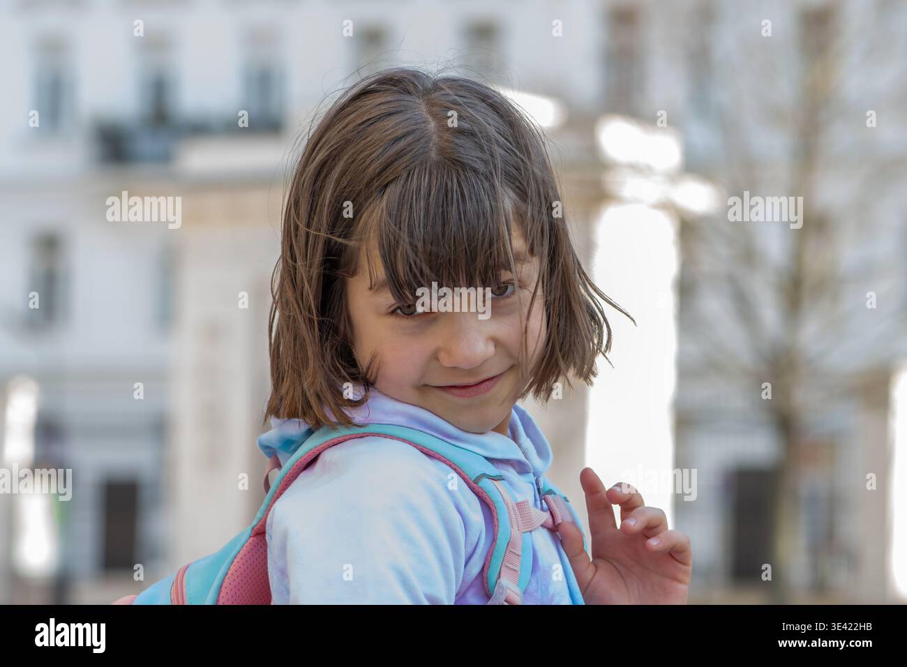 Schoolgirl in hoodie poses outdoors with joyful and confident expression. Stock Photo