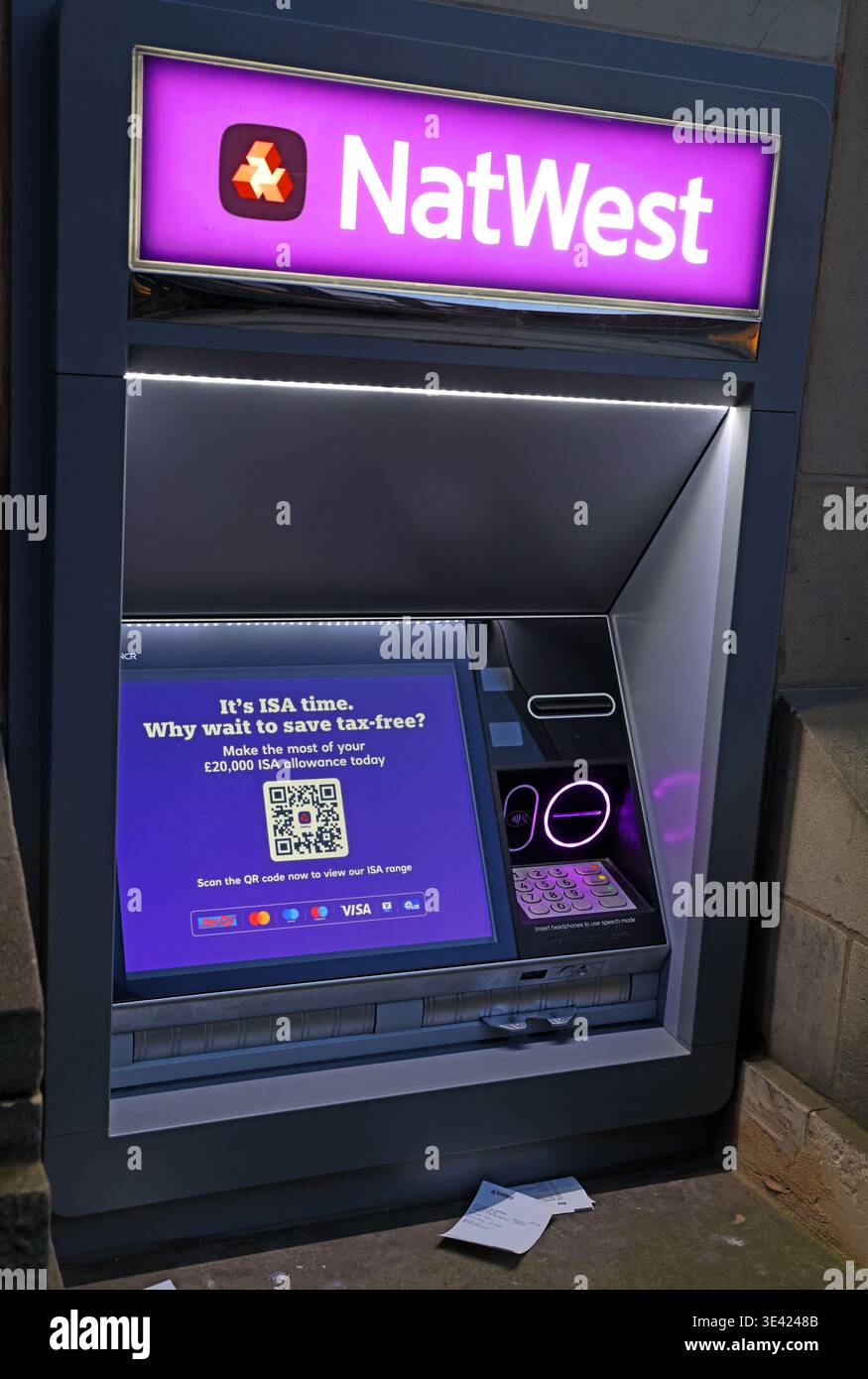 NatWest ATM in Warrington at dusk, showing purple branding and a Cash ISA advert for the April new tax year savings season. Stock Photo