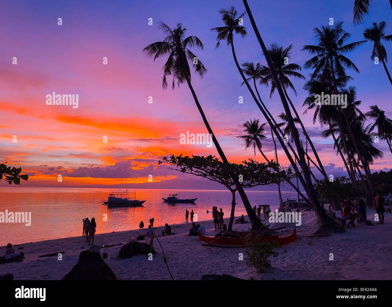 Vibrant and colourful sunset at Little Paliton Beach, Siquijor, Philippines, with palm silhouettes and boats on calm tropical waters. - Smartphone Captured Stock Image