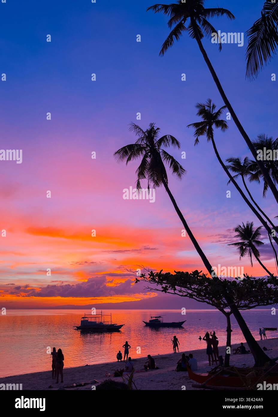 Vibrant and colourful sunset at Little Paliton Beach, Siquijor, Philippines, with palm silhouettes and boats on calm tropical waters. - Smartphone Captured Stock Image