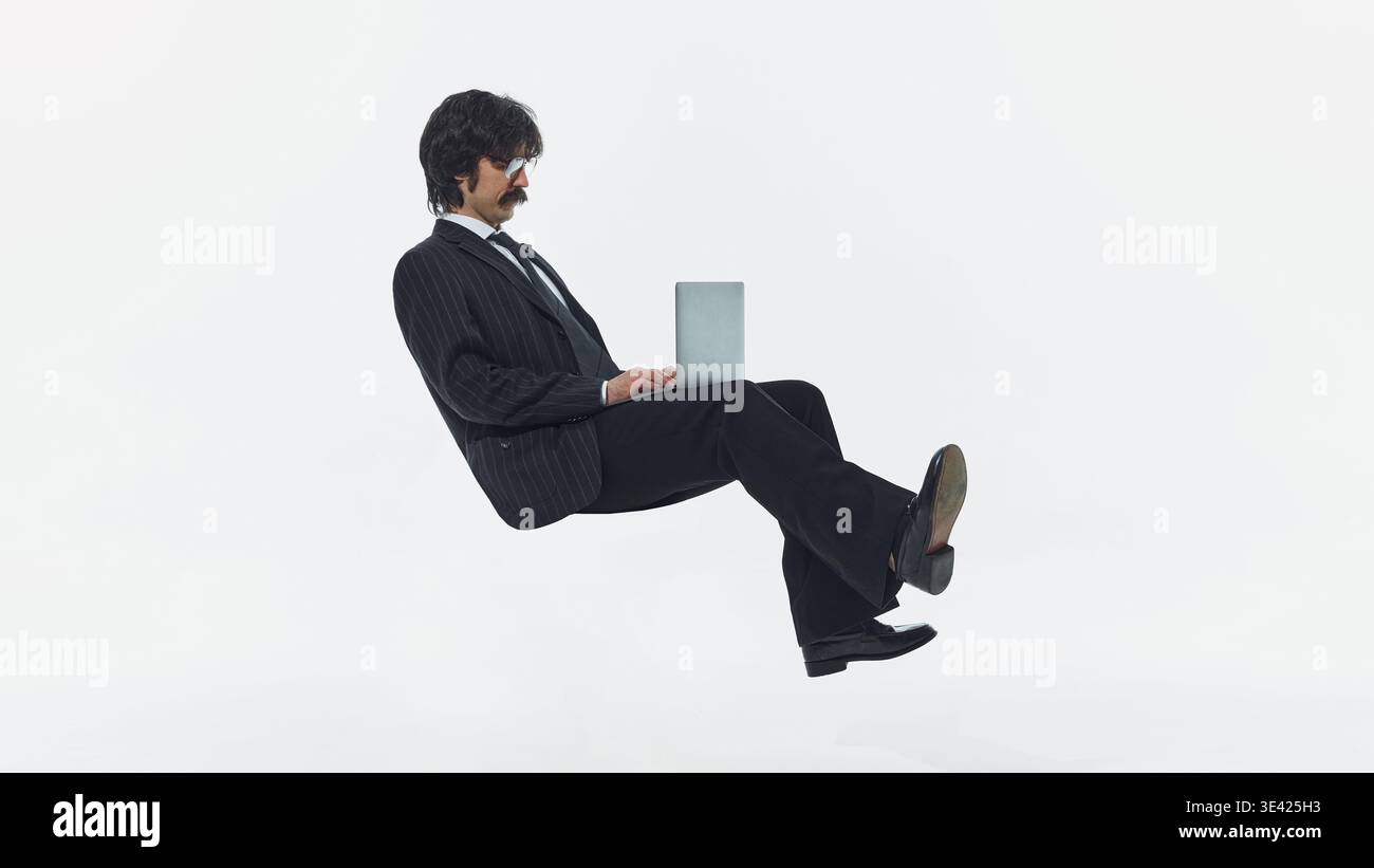Businessman floating while using laptop isolated on white background studio shot. Stock Photo
