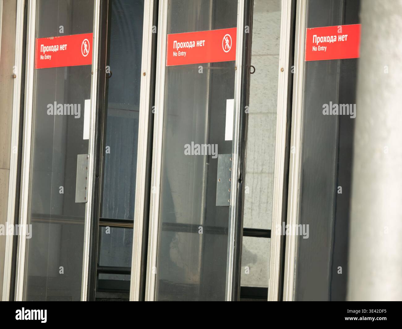Glass doors with no entry sign at building entrance. Red warning label ...