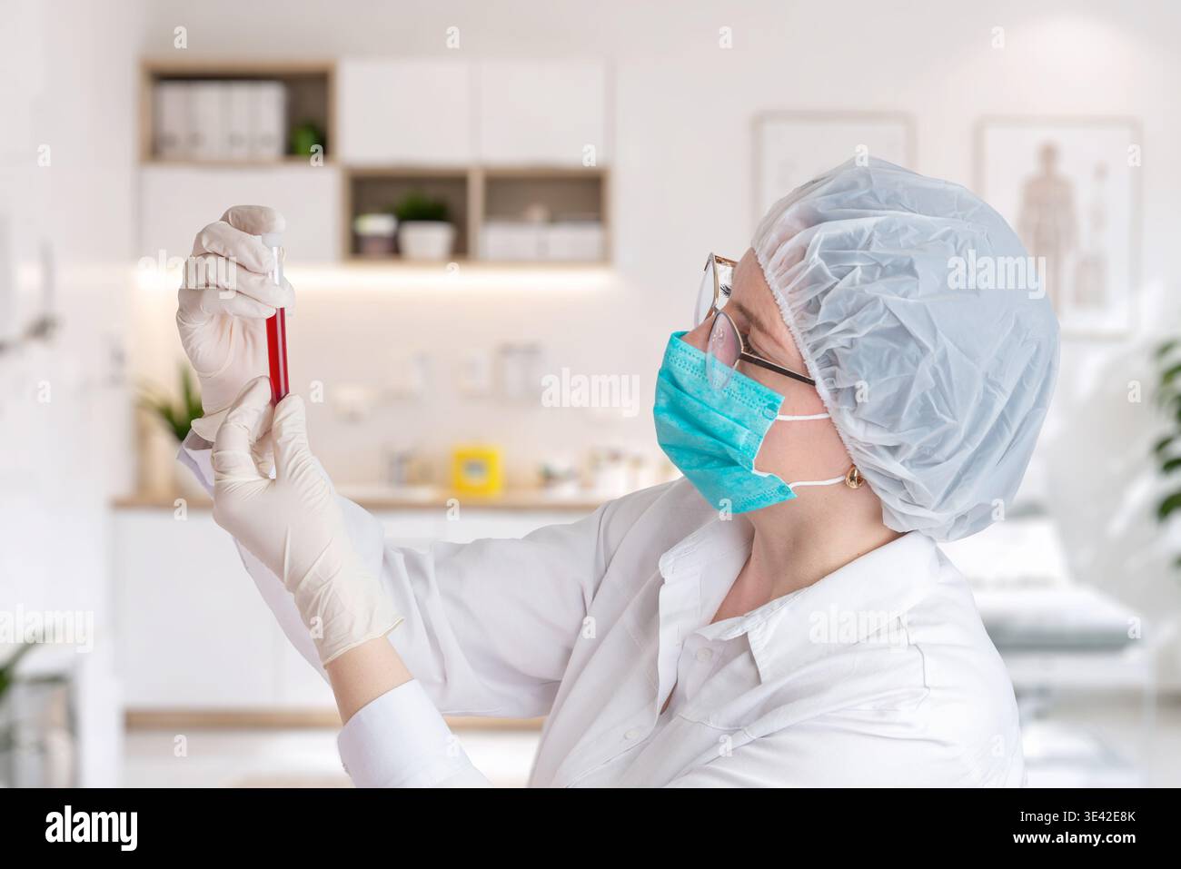 Scientist carefully examining blood sample in test tube, healthcare research and laboratory diagnostics concept with modern clinical interior Stock Photo
