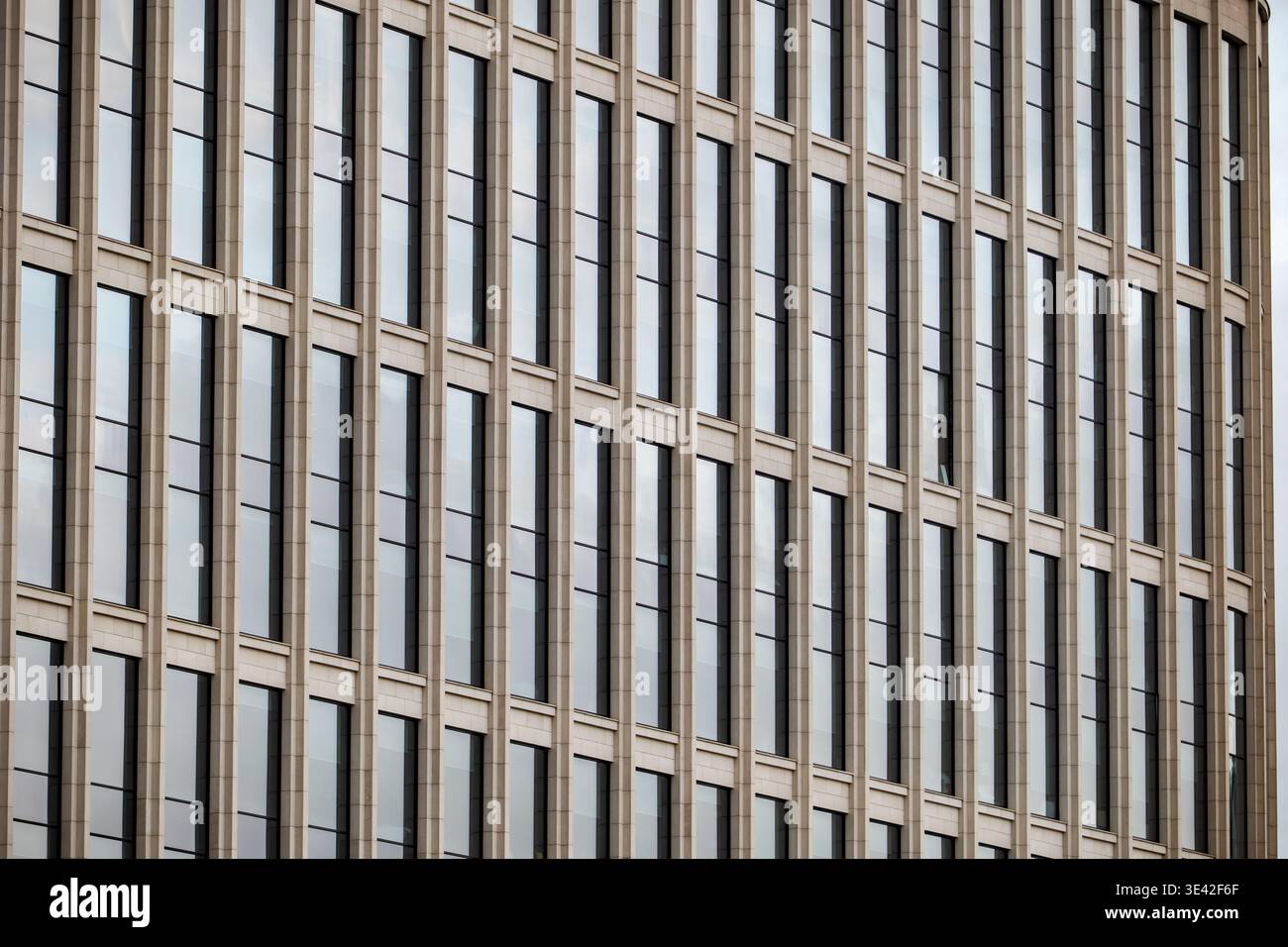 Modern building facade presenting repeating vertical glass windows and structure Stock Photo