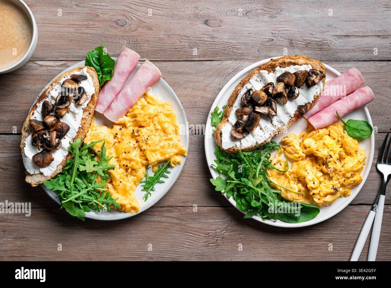Healthy balanced breakfast plates. Scrambled eggs, greens, ham, sandwich with cream cheese and fried mushrooms.  Breakfast for two, breakfast together Stock Photo