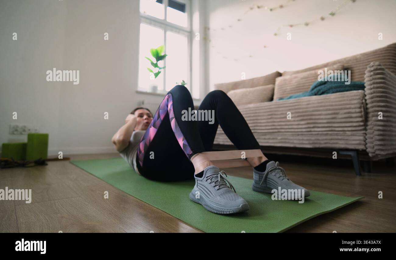 Girl Doing Fitness Exercises With Rubber Resistance Band, Doing Abs Exercises On A Floor Stock Photo