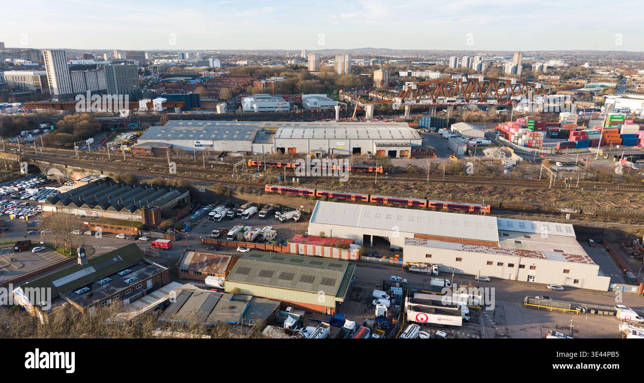 Three passenger trains on four track railway line with HS2 Bellingham Bridge construction and container yard in Birmingham Stock Photo