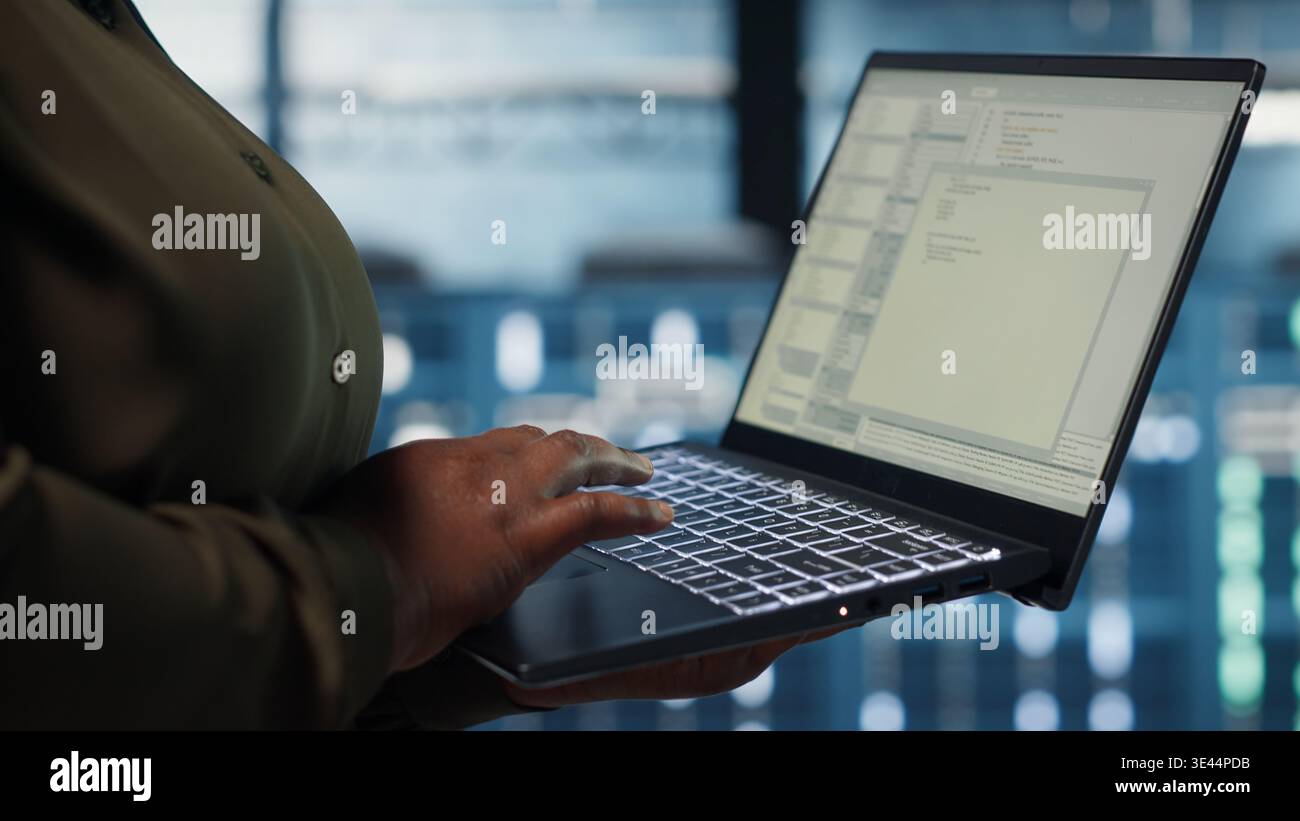 Close up of software developer working in data center to optimize network infrastructure. Programmer in server farm diagnosing and resolving equipment malfunctions using device Stock Photo