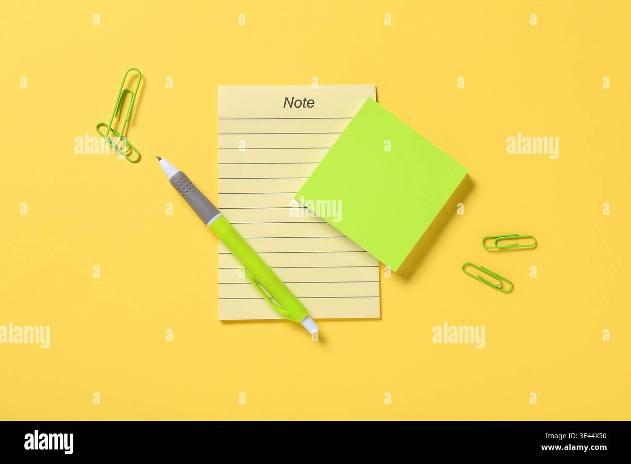 Blank note and sticky notes with pen on yellow background Stock Photo