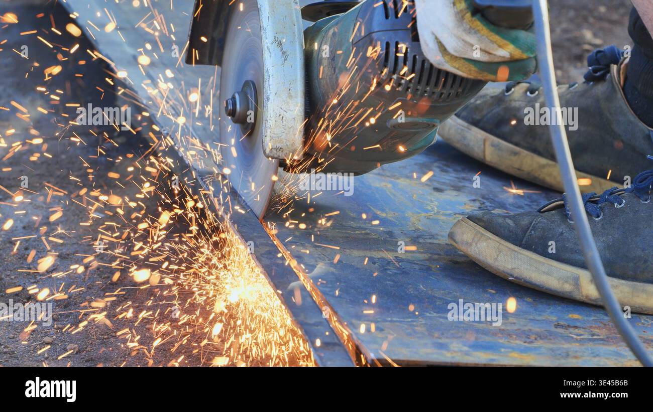 Worker cutting metal using an angle grinder, producing sparks in Moscow Stock Photo