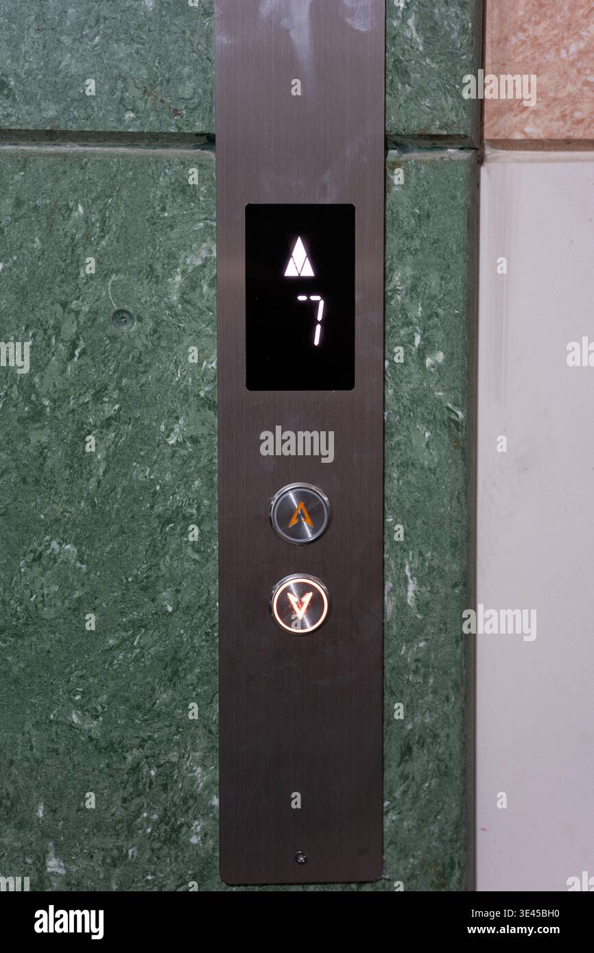 Elevator panel with floor indicator showing 7th floor, modern metallic control buttons, green Stock Photo
