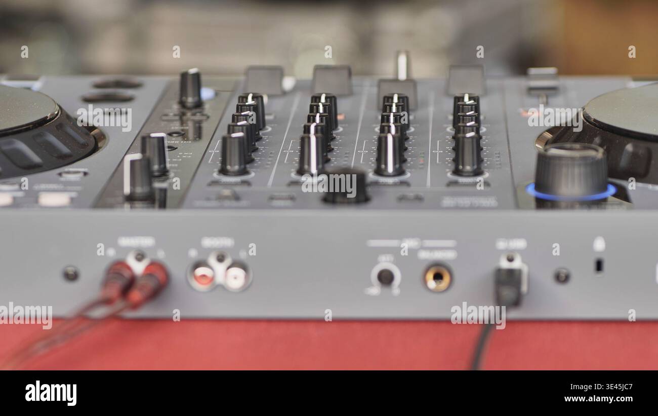 DJ controller with connected cables and knobs for mixing music at an event Stock Photo