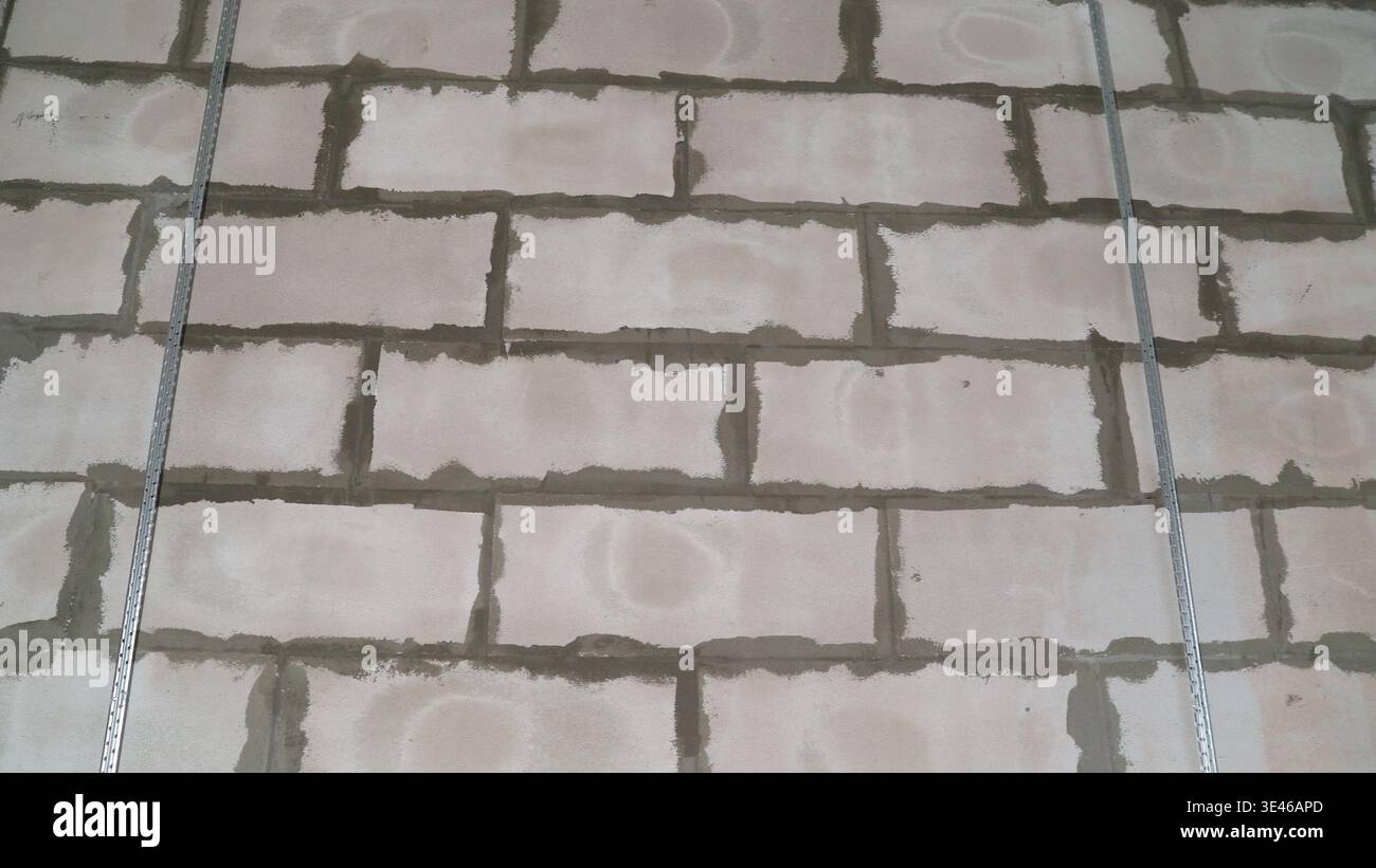 Close-up of metal profiles attached to a cinder block wall, providing support during a building construction or renovation project Stock Photo