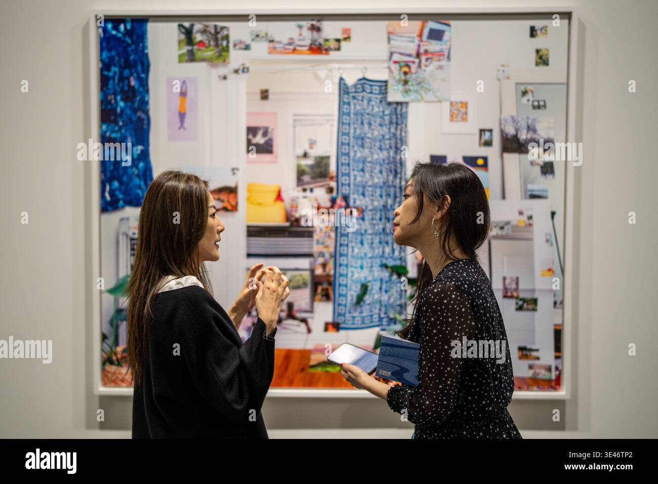 A woman talking to another woman in front of an painting hangin on the ...