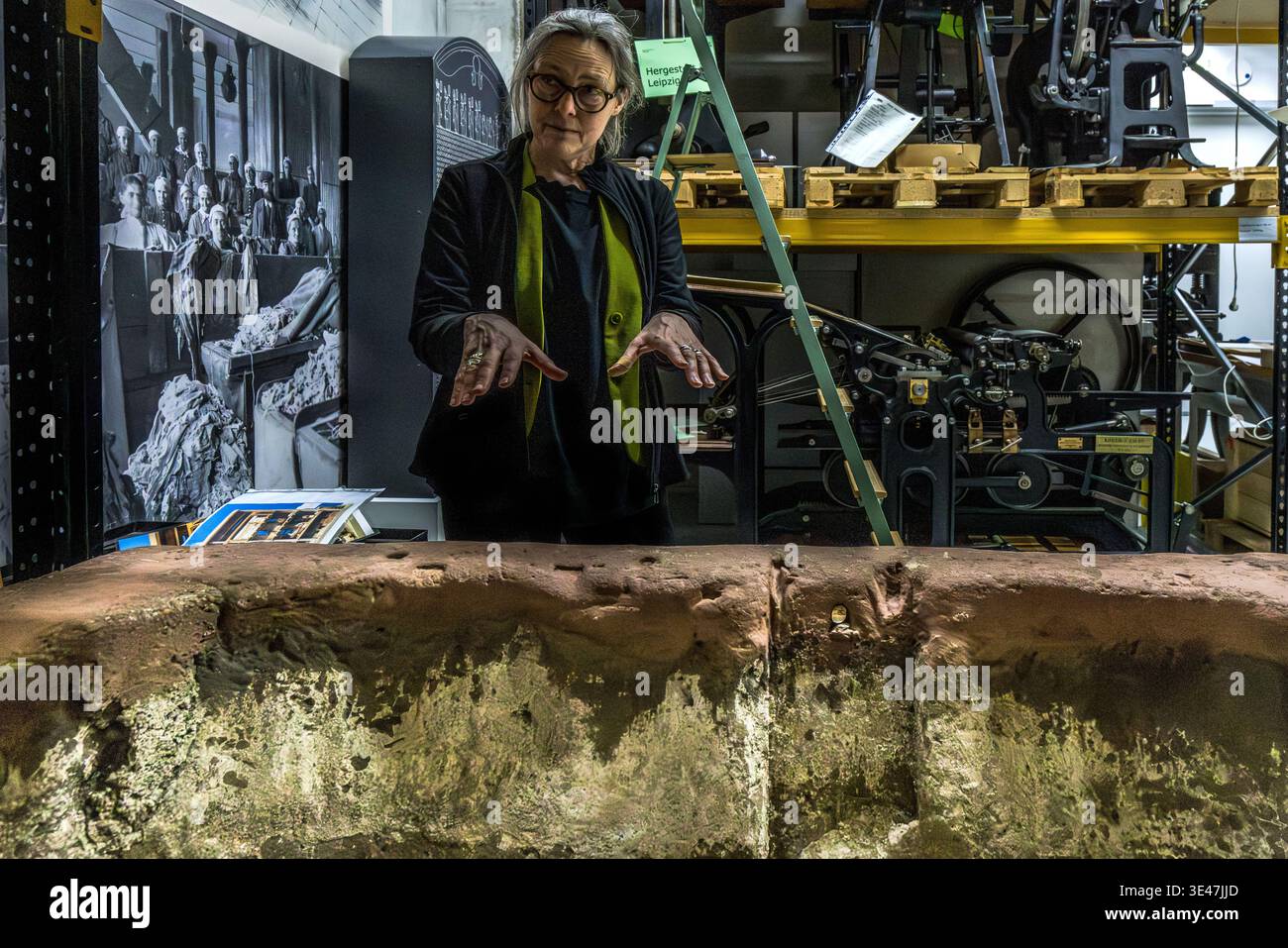Stephanie Jacobs (Director of the German Book and Writing Museum) in the cultural history collection displaying printing tools. Here is a stone trough from 1789, in which rags were turned into a pulp for paper-making. Leipzig, Saxony, Germany Stock Photo