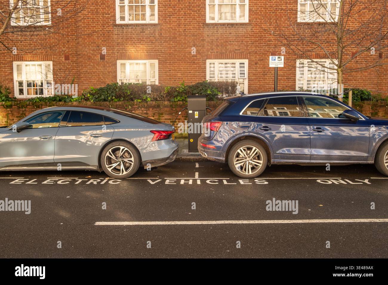 LONDON - FEBRUARY 4, 2026: Two electric cars charging in dedicated EV bay on residential street SW10 Stock Photo