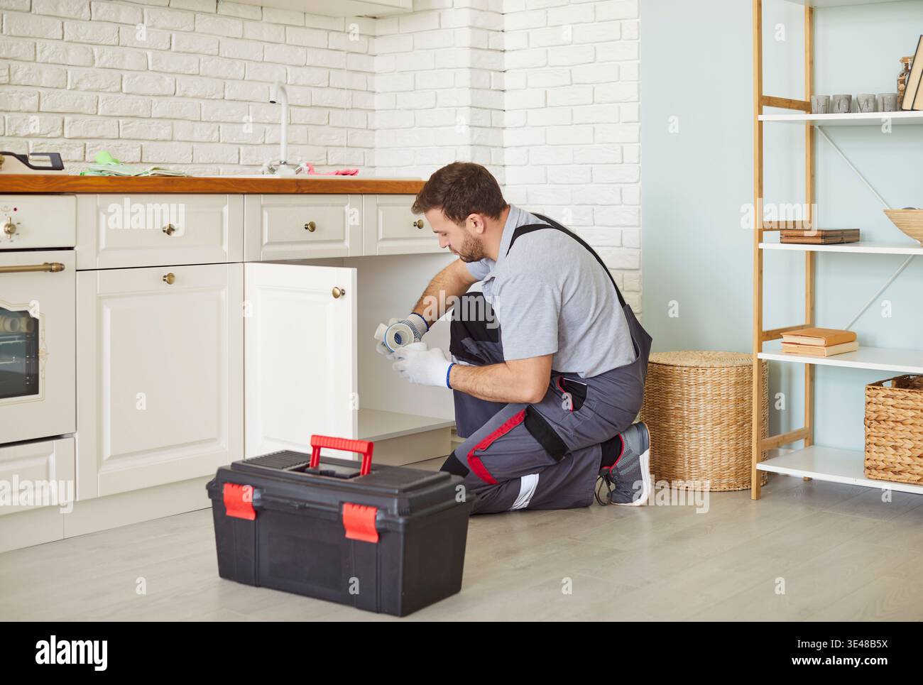 Focused Plumber Fixing Sink In Kitchen Stock Photo