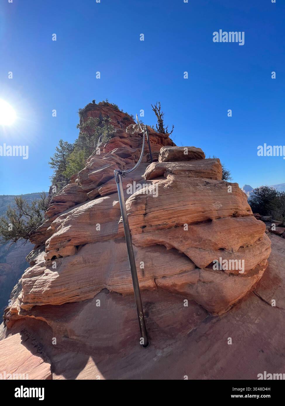 Steep chain-assisted descent with hikers on red rock ridge, Angels Landing trail, Zion National Park, Utah, USA - Smartphone Captured Stock Image