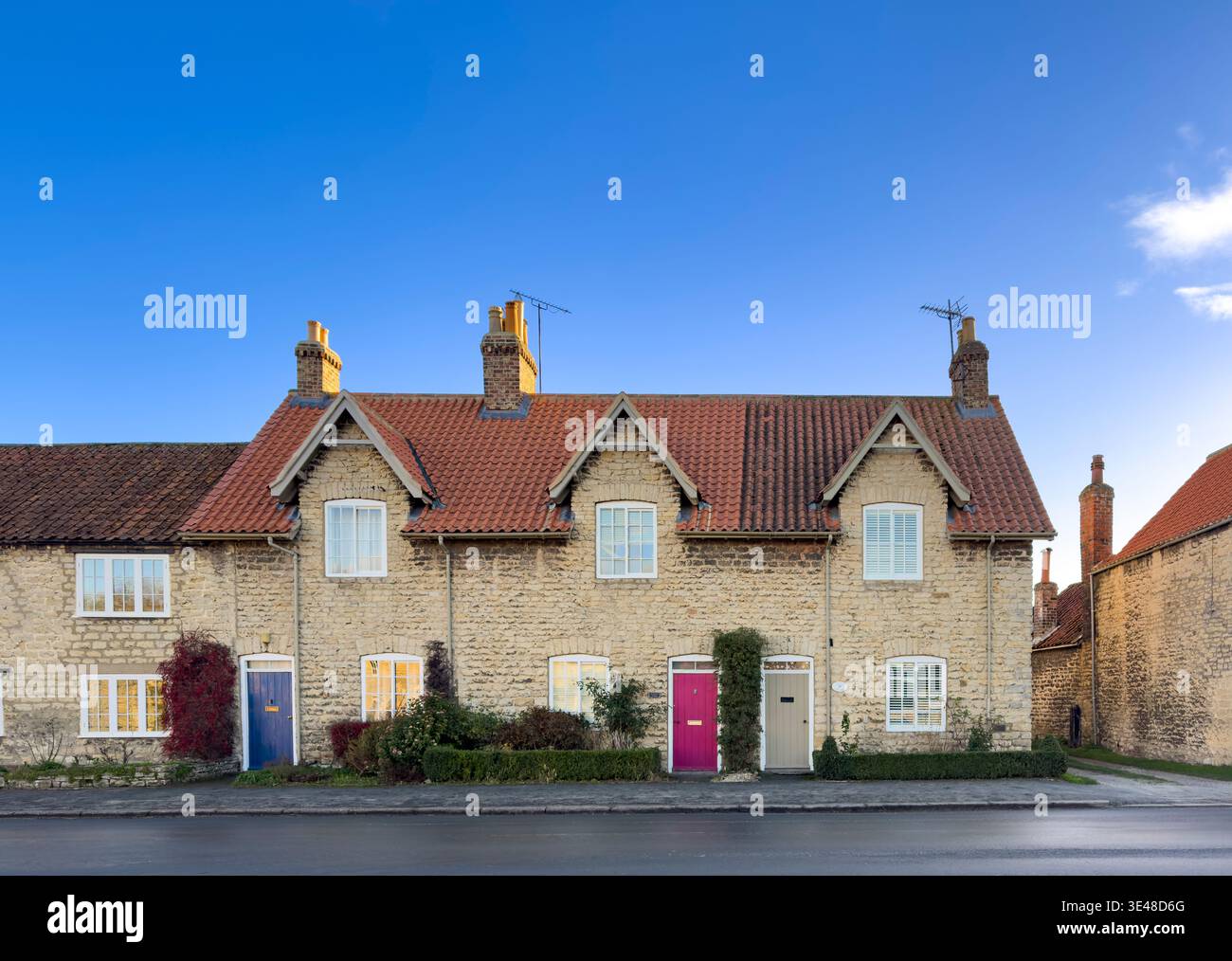 Row of traditional stone cottages with colourful doors in the village of Hovingham, North Yorkshire Stock Photo