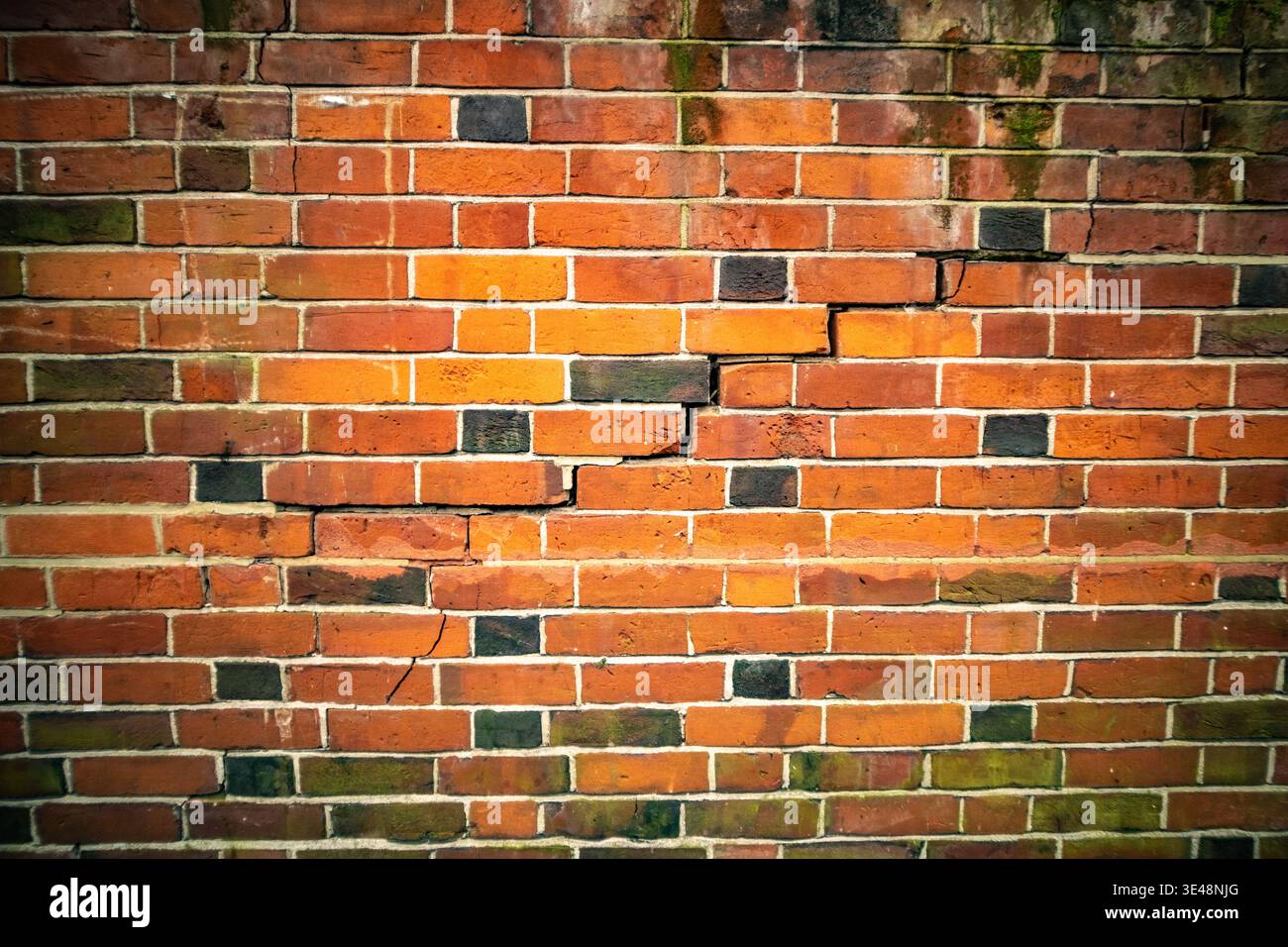 Weathered red British brick wall with dramatic crack texture background Stock Photo