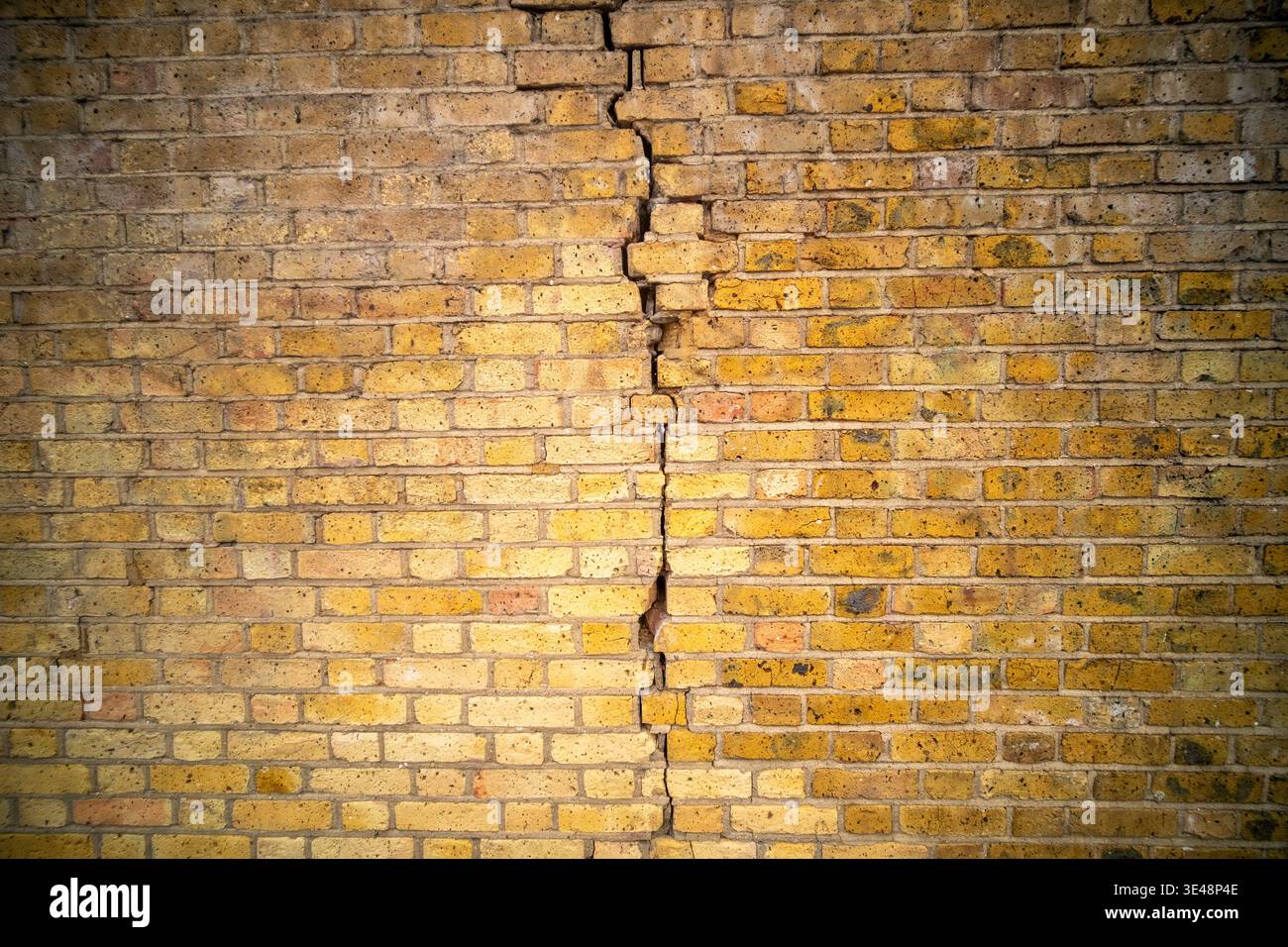 Weathered red British brick wall with dramatic crack texture background Stock Photo