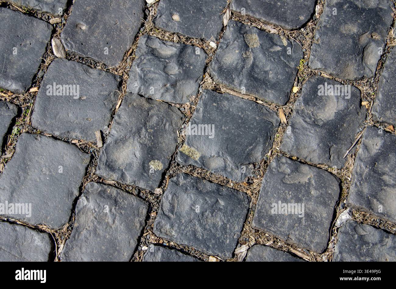 Dark grey ancient cobblestone pavement creating a textured background pattern Stock Photo