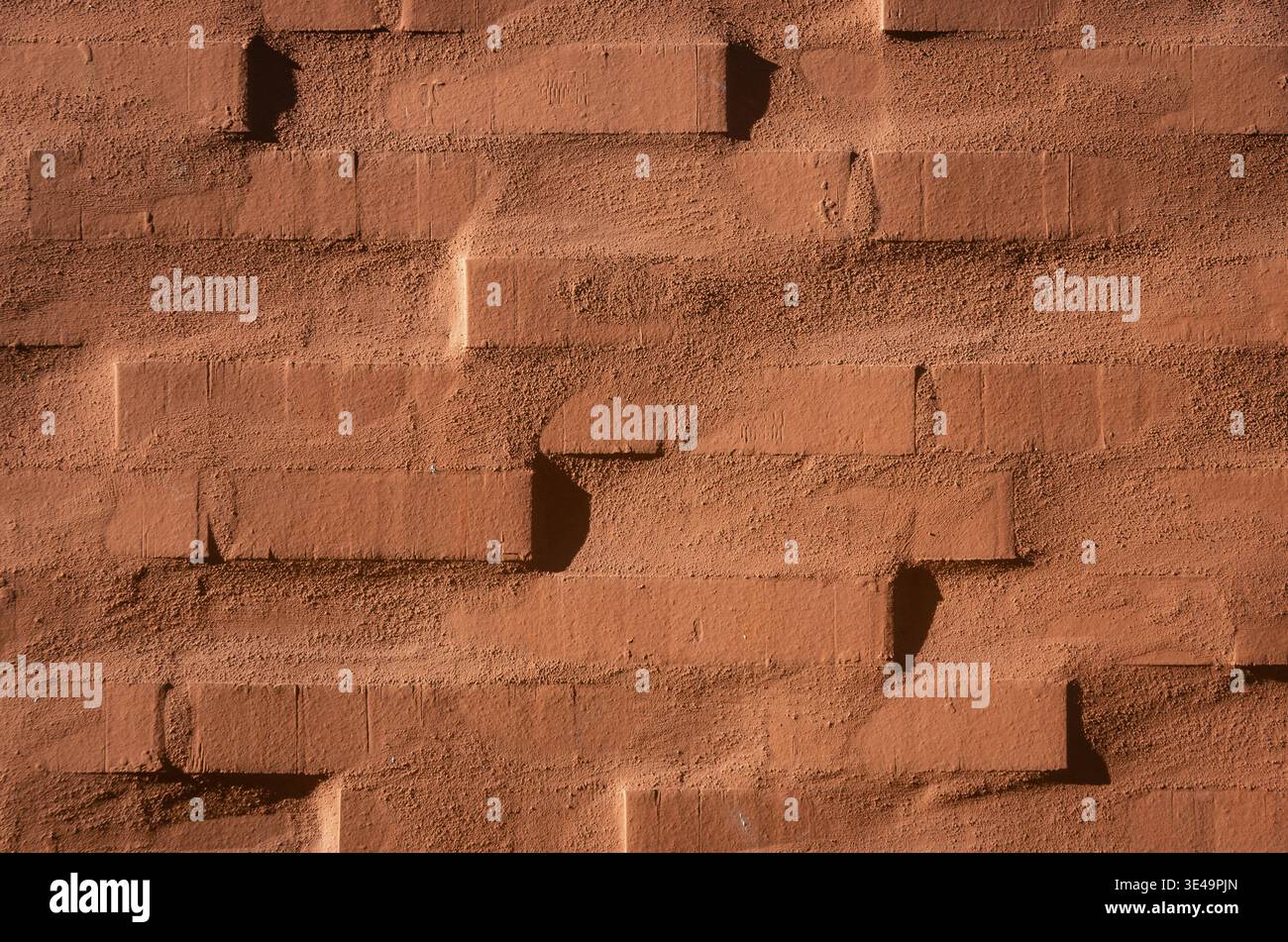Rough red brick wall texture with strong shadows forming a geometric pattern Stock Photo