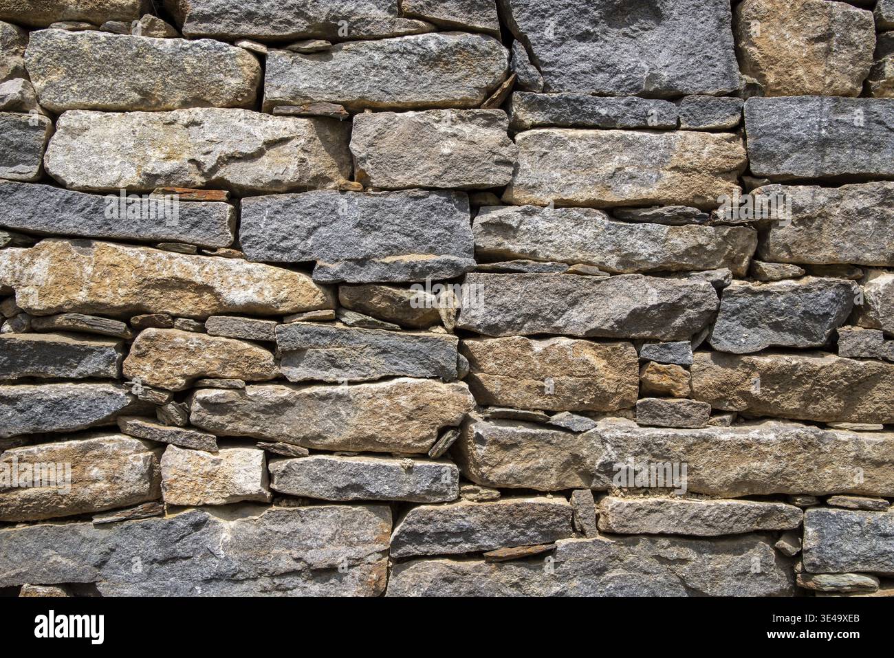 Stone wall showing irregular blocks creating a strong pattern and rustic background Stock Photo