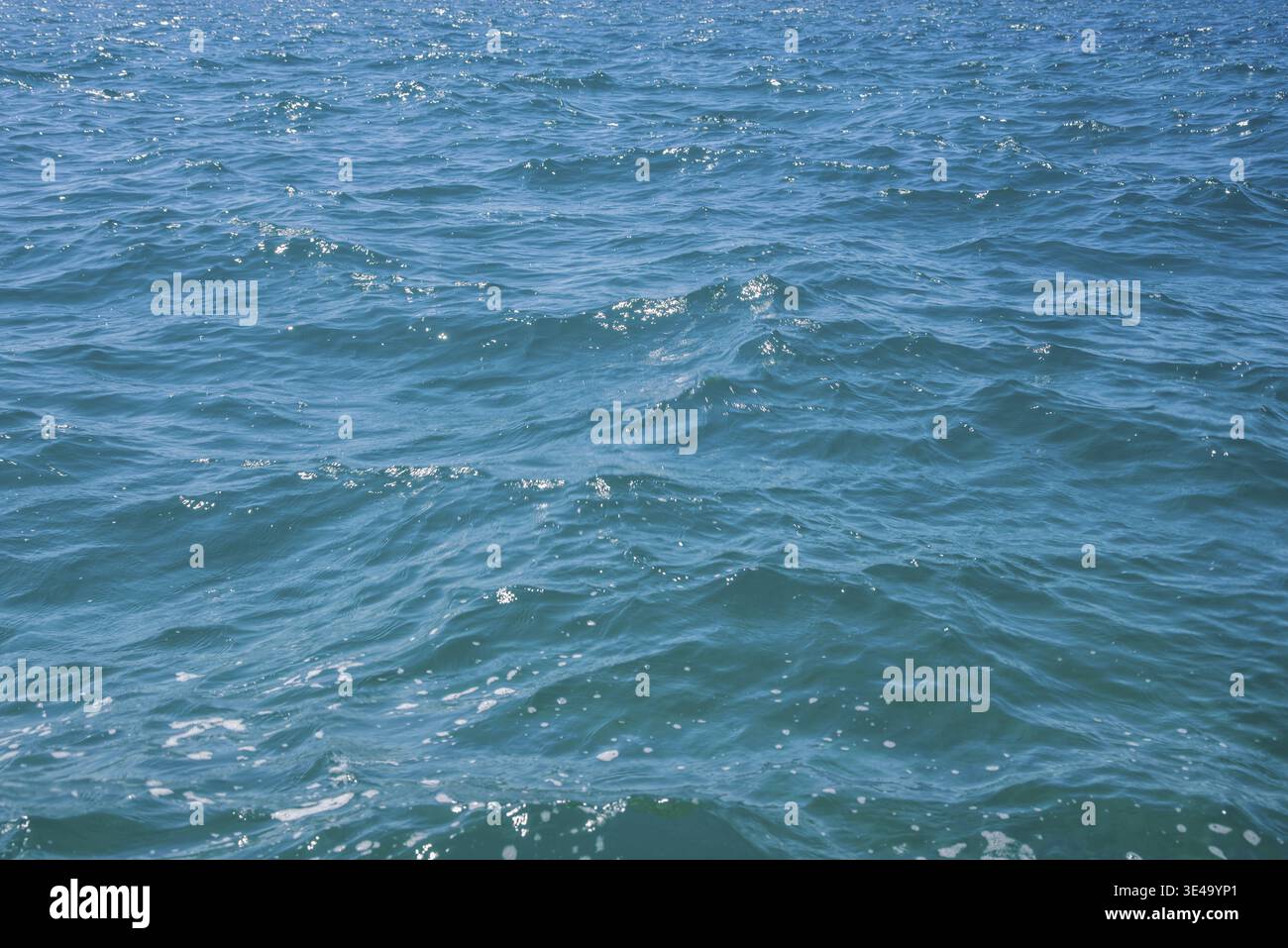 Ocean water surface ripples reflecting sunlight, creating a dynamic turquoise blue background Stock Photo
