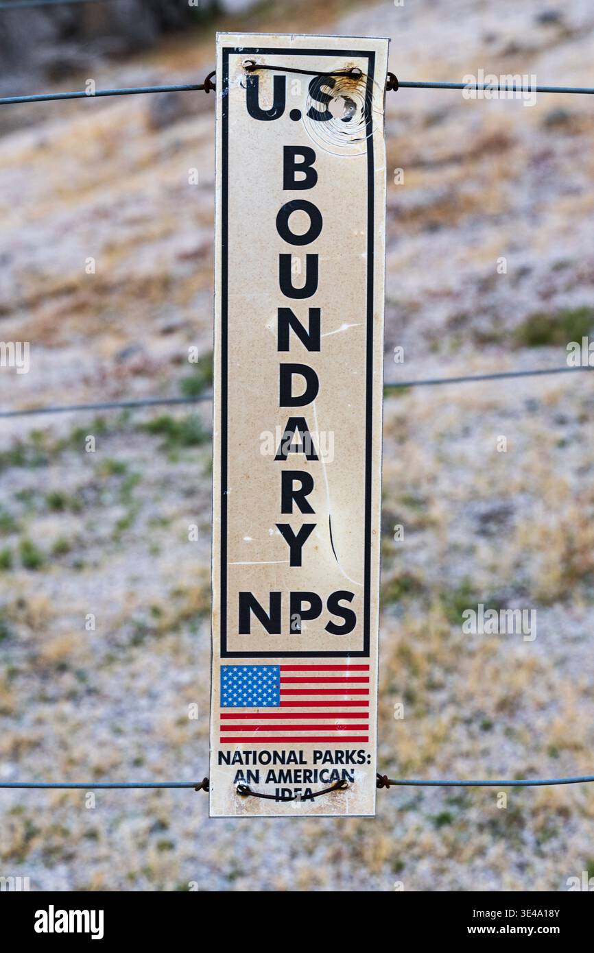 US National Park boundary sign on a wire fence that has been shot with a bullet hole in it Stock Photo