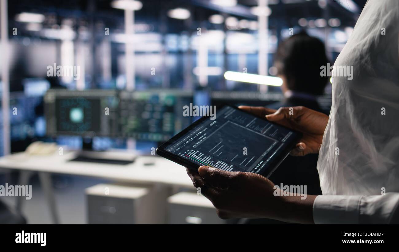 Close up of data center programmer using tablet, writing code for resource optimization, performing updates. Server room employee using device, compiling software patches to fix bugs, camera A Stock Photo