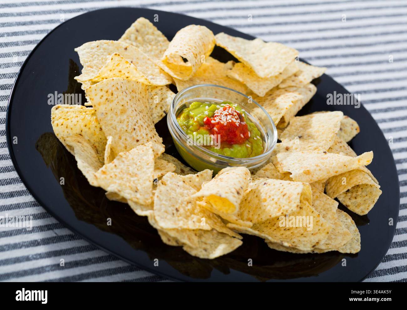 Nachos chips with sauces on black plate Stock Photo