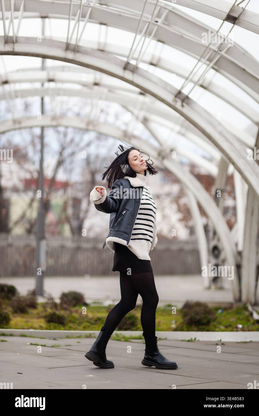 Girls Structur Girl dancing joyfully in a modern outdoor structure during a bright day ...