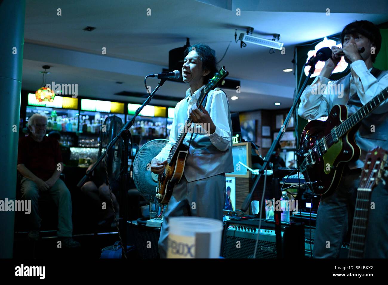 "George Harrison" and (right-handed) "Paul McCartney" perform live with the tribute band The Bangkok Beatles in Hua Hin, Thailand. Stock Photo