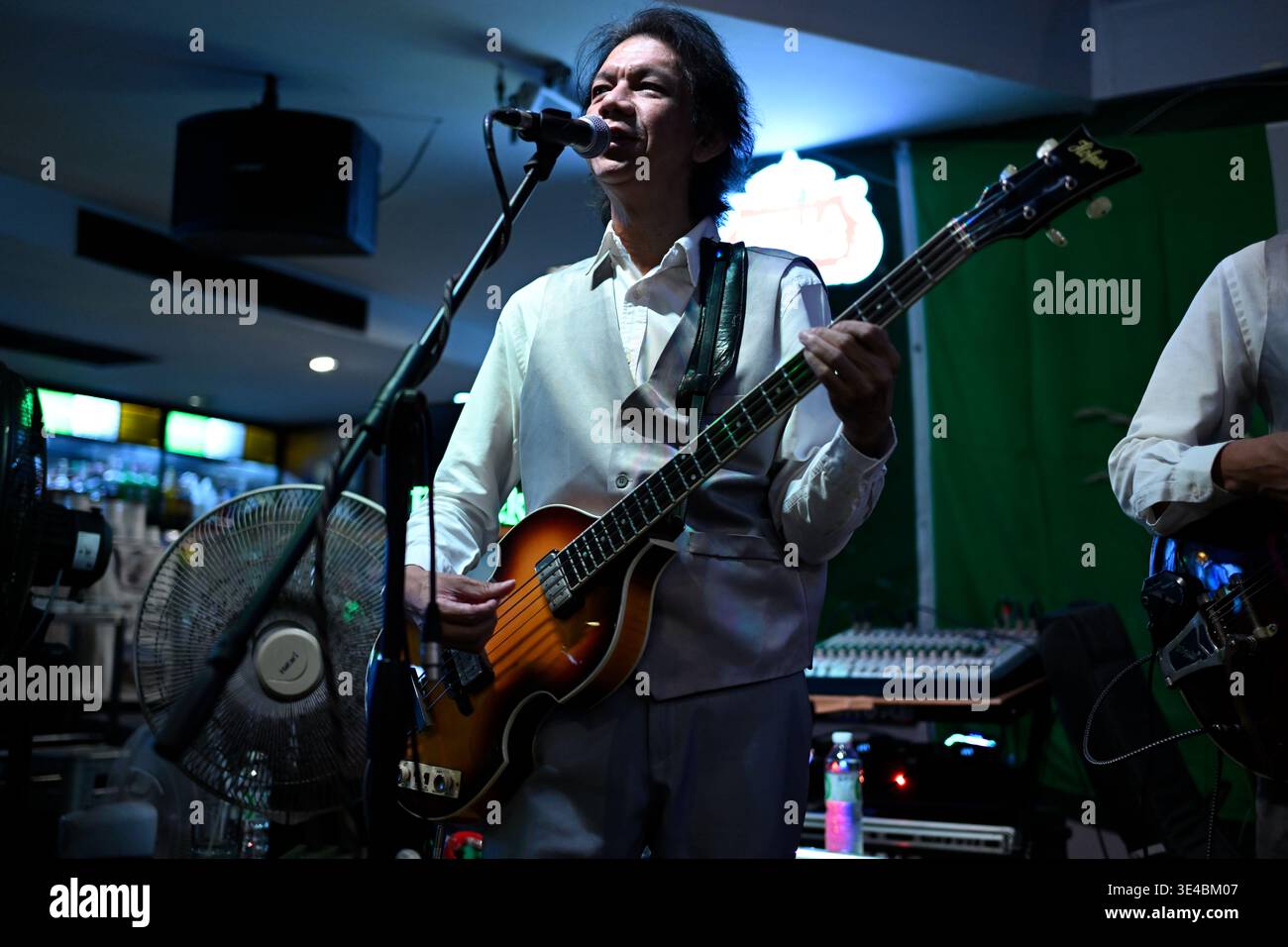 A right-handed "Paul McCartney" performs live with the tribute band The Bangkok Beatles in Hua Hin, Thailand. Stock Photo