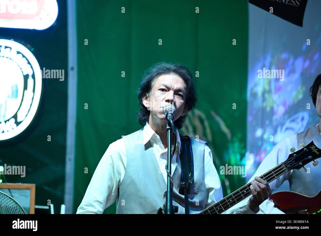 A right-handed "Paul McCartney" performs live with the tribute band The Bangkok Beatles in Hua Hin, Thailand. Stock Photo