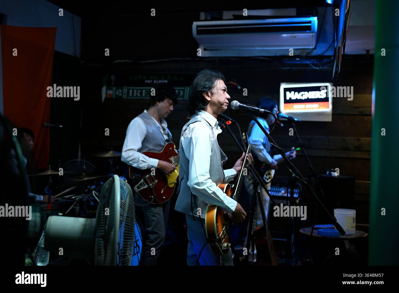 "George Harrison" and (right-handed) "Paul McCartney" perform live with the tribute band The Bangkok Beatles in Hua Hin, Thailand. Stock Photo