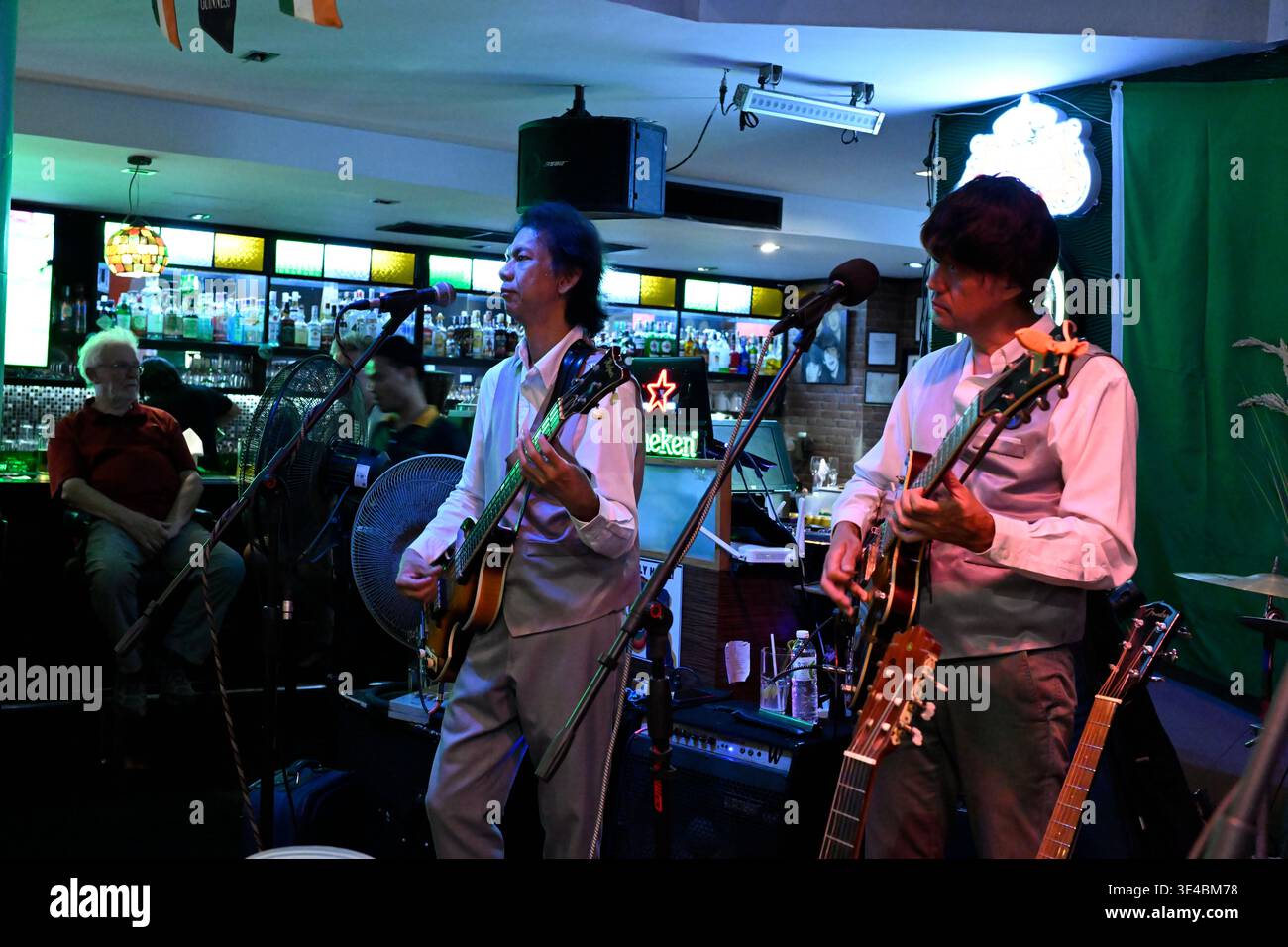 "George Harrison" and (right-handed) "Paul McCartney" perform live with the tribute band The Bangkok Beatles in Hua Hin, Thailand. Stock Photo