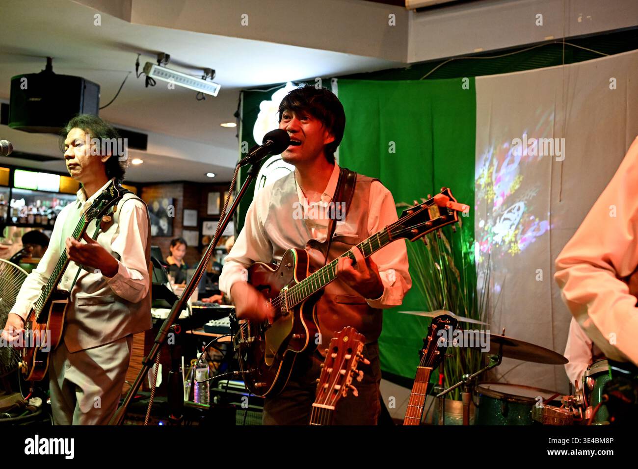 "George Harrison" and (right-handed) "Paul McCartney" perform live with the tribute band The Bangkok Beatles in Hua Hin, Thailand. Stock Photo