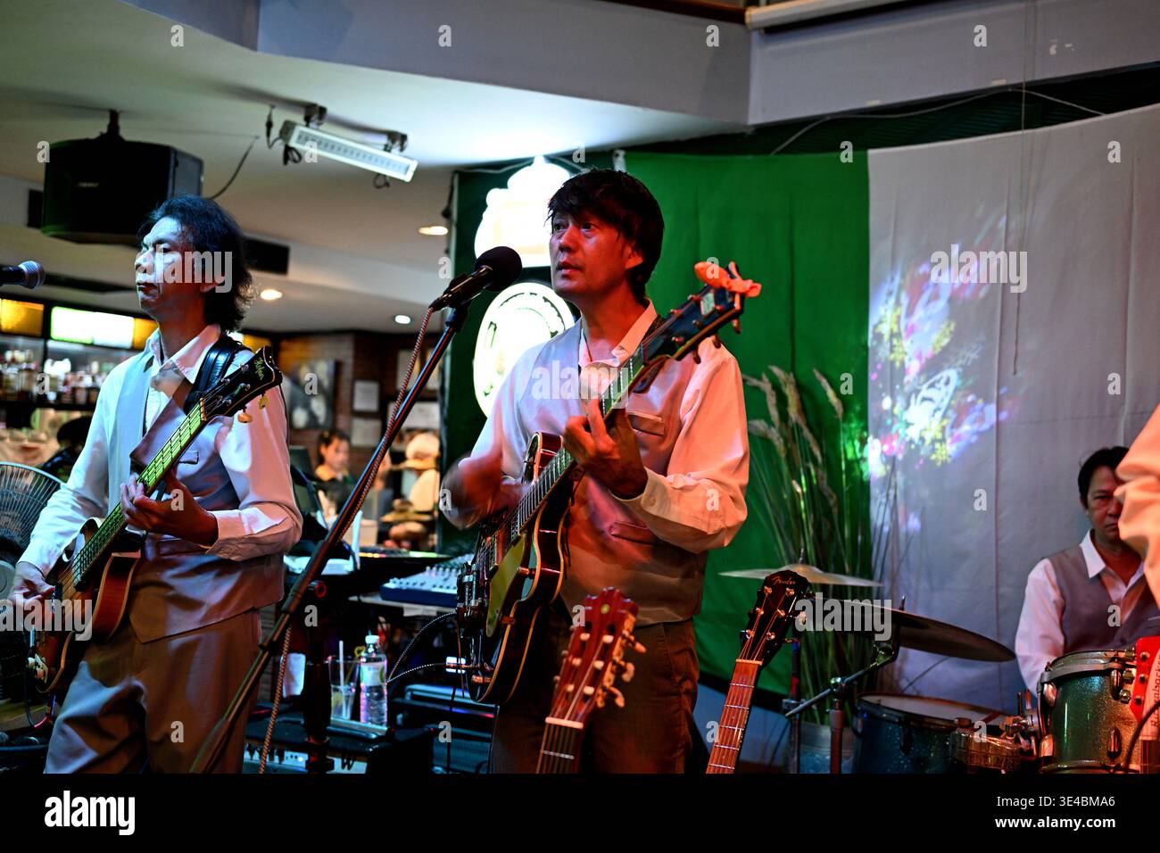 "George Harrison" and (right-handed) "Paul McCartney" perform live with the tribute band The Bangkok Beatles in Hua Hin, Thailand. Stock Photo