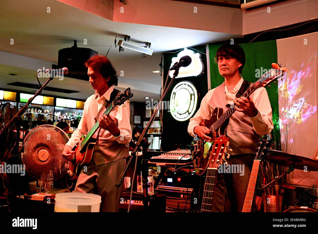 "George Harrison" and (right-handed) "Paul McCartney" perform live with the tribute band The Bangkok Beatles in Hua Hin, Thailand. Stock Photo