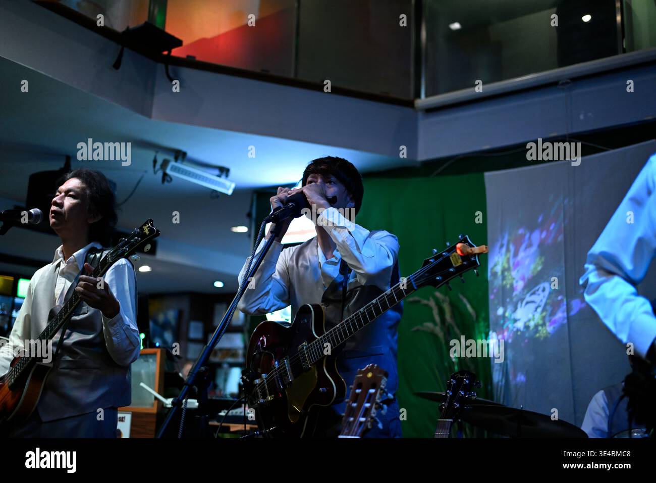 "George Harrison" and (right-handed) "Paul McCartney" perform live with the tribute band The Bangkok Beatles in Hua Hin, Thailand. Stock Photo