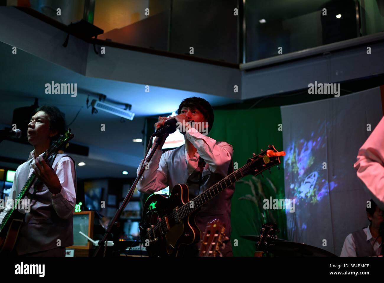 "George Harrison" and (right-handed) "Paul McCartney" perform live with the tribute band The Bangkok Beatles in Hua Hin, Thailand. Stock Photo
